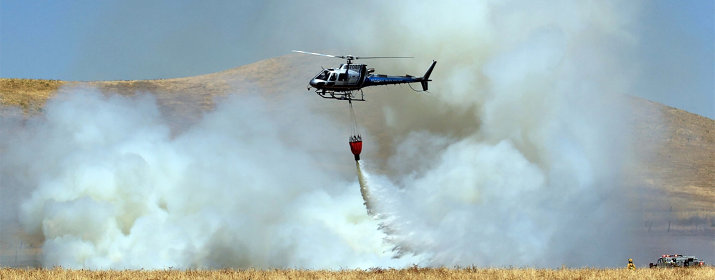 Helicopter dropping fire suppressant on a controlled burn in Rush Ranch.