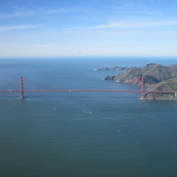 blue water of San Francisco Bay, red Golden Gate bridge, and the waters outside the Golden Gate and surrounding land on both sides